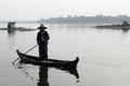 U-BEIN BRIDGE/AMARAPURA, MYANMAR JAN 22, 2016: A woman is navigating her boat on the Taungthaman Lake that is being crossed by the Royalty Free Stock Photo