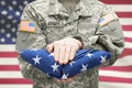 US Army young soldier holding carefully folded USA flag before his chest Royalty Free Stock Photo