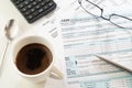 U.S. income tax return form, cup of coffee, pen, calculator and glasses