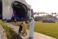 Exhibition EXPO 2020. Open air concert. Family in national dress with woman in wheelchair stand near stage