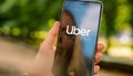 Uber driver holding smartphone in car. Uber is an American company offering different transportation services online Royalty Free Stock Photo