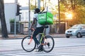 Uber Eats bicycle messenger in city traffic at sunset