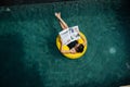 Ubud, Indonesia - February 13 2020: Young woman in a black swimsuit and sunglasses swimming in pool