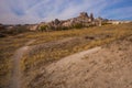 Uchisar, Cappadocia, Turkey: The road on the field goes to the city and the fortress of Uchisar. Rock houses and churches. Rock Royalty Free Stock Photo