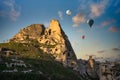 The high mountains in Cappadocia, Uchisar Castle and balloon in the morning are golden light with blue sky.