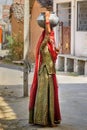 Indian woman with water carried in pot on her head on the street near Udaipur. India