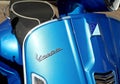 Vespa logo on a new metallic blue scooter.