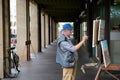 Udine. Italy. August 2023. Authentic side portrait of an elderly male artist, painter drawing on canvas outdoors