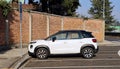 White Citroen C3 Aircross parked at the road side with brickwall on behind. Side view.
