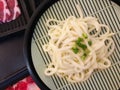 Udon japanese noodle on wooden mat with fresh sliced pork for shabu Royalty Free Stock Photo