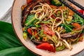 Udon stir fry noodles with beef meat and vegetables in a plate on white wooden background Royalty Free Stock Photo