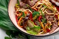 Udon stir fry noodles with beef meat and vegetables in a plate on white wooden background Royalty Free Stock Photo