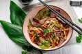 Udon stir fry noodles with beef meat and vegetables in a plate on white wooden background Royalty Free Stock Photo
