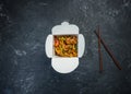 Udon stir fry noodles with chicken in a box on a vintage colored background. Top view. With chopsticks