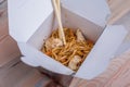 Udon stir fry noodles with chicken in a box on a wooden background