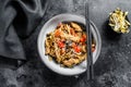 Udon stir-fry noodles with chicken meat and sesame. Black background. Top view