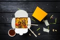 Udon stir fry noodles with meat or chicken in a box. Black background. With chopsticks and sauce. Royalty Free Stock Photo