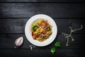 Udon stir fry noodles with meat or chicken and vegetables in a white plate.