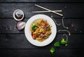 Udon stir fry noodles with meat or chicken and vegetables in a white plate with chopsticks. Royalty Free Stock Photo