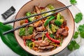 Udon stir fry noodles with pork meat and vegetables in a plate on white wooden background Royalty Free Stock Photo