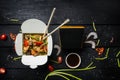 Udon stir fry noodles with seafood in a box on black background. With chopsticks and box for noodles.