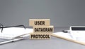 UDP - User Datagram Protocol text on wooden block with notebook,chart and calculator, grey background