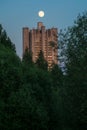 Uenusually large moon over the skyscraper in a summer evening sky. Royalty Free Stock Photo