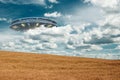 UFO, an alien plate hovering over the field, hovering motionless in the air. Unidentified flying object, alien invasion, Royalty Free Stock Photo