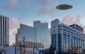 UFO Flying Saucer hovering above tall buildings