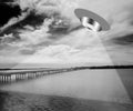 UFO or UAP over a lake beaming light over the water and bridge