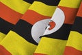 Uganda flag with big folds waving close up under the studio light indoors. The official symbols and colors in banner