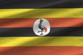 Uganda flag with big folds waving close up under the studio light indoors. The official symbols and colors in banner