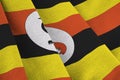 Uganda flag with big folds waving close up under the studio light indoors. The official symbols and colors in banner