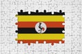 Uganda flag in frame of white puzzle pieces with missing central part