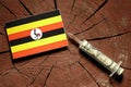 Uganda flag on a stump with syringe injecting money