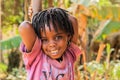 Ugandan African girl with dreadlocks smiles very cute while playing on the street of Kampala suburb