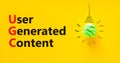 UGC user generated content symbol. Concept words UGC user generated content on a beautiful yellow background. Green light bulb Royalty Free Stock Photo