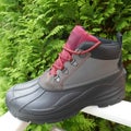 Rugged, waterproof outdoor boot for men, side view, in front of a green hedge