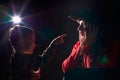 Ugle oman in red sweater and pirate hat with curly hair posing with small boy on black background. Actress mother and