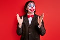 ugly clown man wearing black suit costume and halloween makeup grimacing making performance