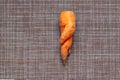 Ugly deformed twisted carrot on a brown wicker rustic background, ugly food, zero waste concept, top view