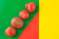 Ugly food concept, deformed tomatoes on the red, green and yellow background, copy space, creative geometric image