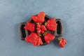 Ugly fruits. Abnormal strawberry shape. Berries in a wooden plate on a blue background. Top view, copy space