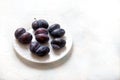 Ugly funny accrete plums lie on a white porcelain plate. Vegetarian food concept. Copy space Royalty Free Stock Photo