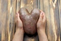 An ugly potato in the shape of a heart in the hands. of natural vegetables