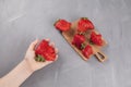 Ugly strawberries on a wooden serving board. A fresh, ripe funny-shaped strawberry lies in a child`s hand