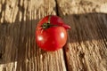 Ugly tomato on an old wooden board. Concept - eating vegetables and fruits that are imperfect in shape