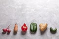 Ugly vegetables laid out in row on grey concrete background.