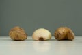 Ugly vegetables. Potatoes and onions on a white wooden background