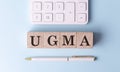 UGMA on wooden cubes with pen and calculator, financial concept